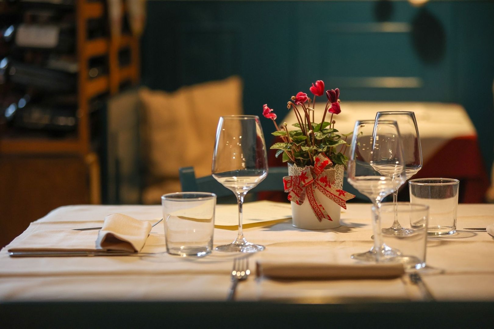 Sfeervol gedekte tafel met wijnglazen en rode bloemen in een restaurant