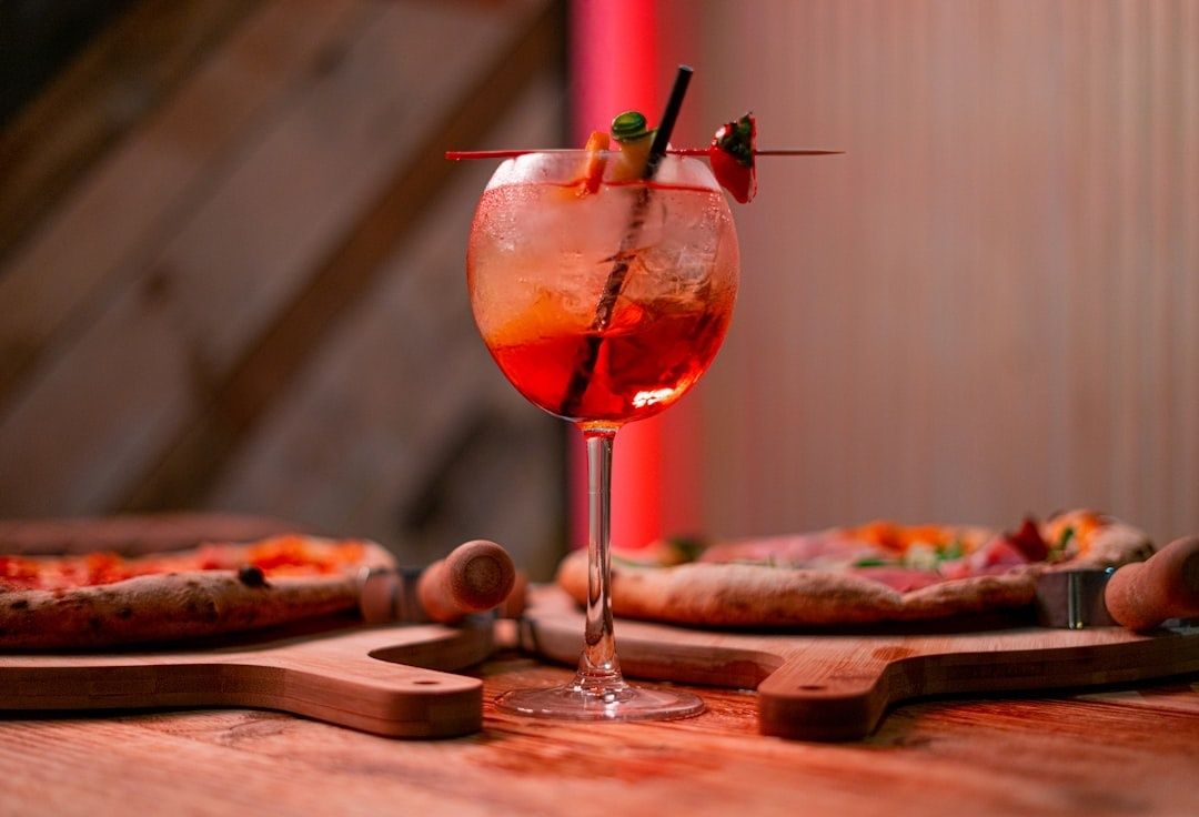 Rode spritzcocktail met garnering tussen pizza