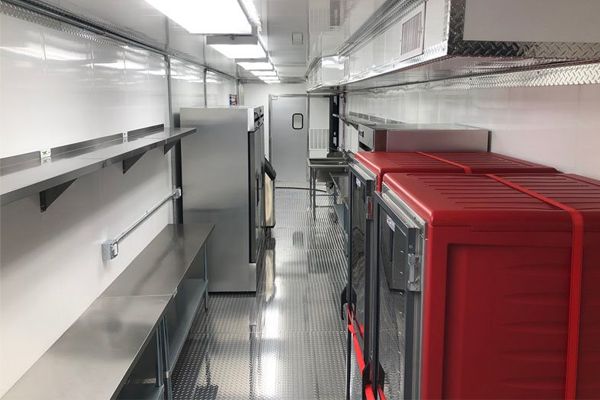 Interieur van een professioneel ingerichte mobiele keuken met roestvrijstalen werkbladen.